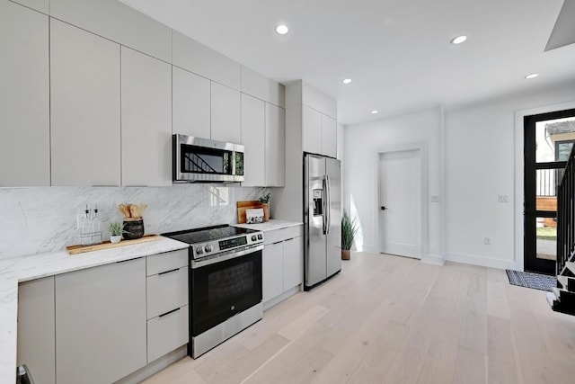 4703 Mount Vernon Dr Unit 2, Austin, TX 78745 - kitchen featuring appliances with stainless steel finishes, light wood-style floors, decorative backsplash, modern cabinets, and light countertops
