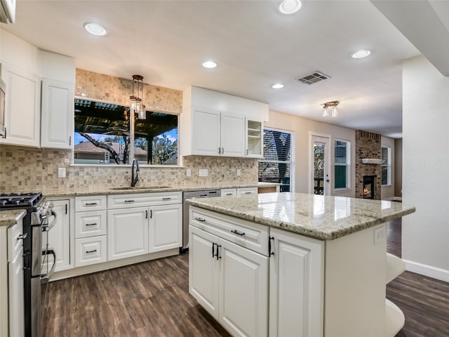 716 Shiny Rock Dr, Austin, TX 78748 - kitchen with appliances with stainless steel finishes, a sink, dark wood-type flooring, decorative backsplash, and a center island