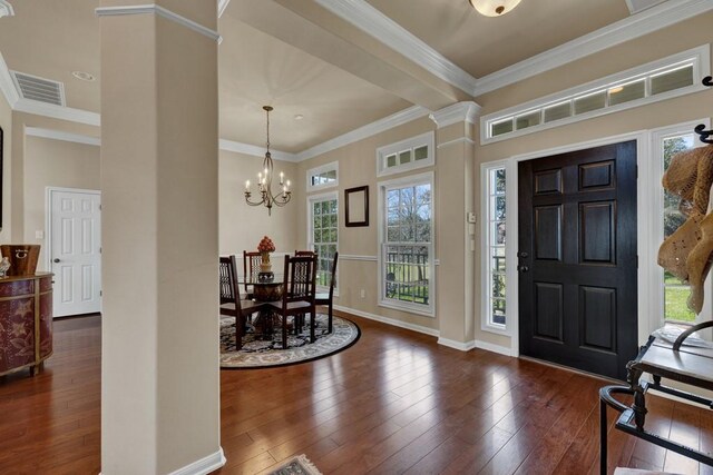 entryway with hardwood / wood-style flooring, ornate columns, baseboards, ornamental molding, and a notable chandelier