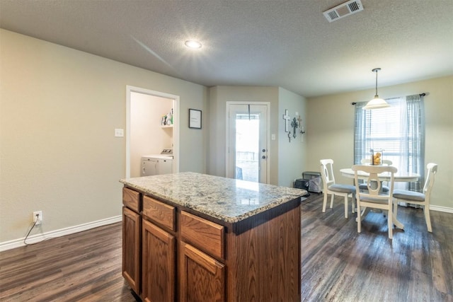 6806 Ambrose Cir, Temple, TX 76502 - kitchen featuring dark wood-style floors, baseboards, visible vents, pendant lighting, and washer and clothes dryer