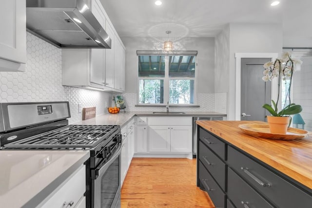402 Irma Dr Unit B, Austin, TX 78752 - kitchen with gas stove, extractor fan, butcher block counters, white cabinetry, and backsplash