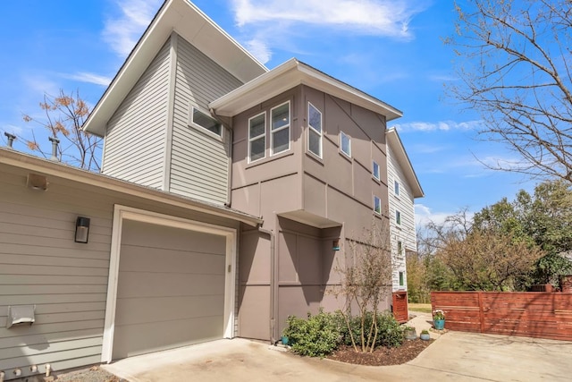 402 Irma Dr Unit B, Austin, TX 78752 - view of property exterior with concrete driveway, a garage, stucco siding, and fence