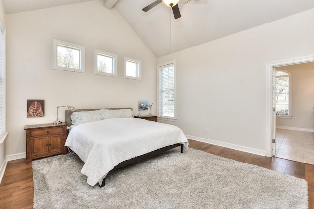 bedroom with lofted ceiling with beams, baseboards, wood finished floors, and multiple windows