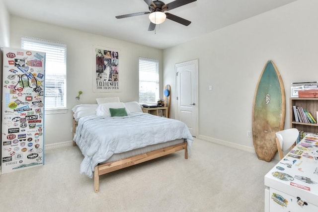 bedroom with light carpet, a ceiling fan, and baseboards