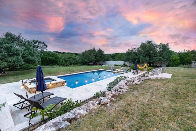 pool at dusk featuring a lawn, a patio, and a pool with connected hot tub