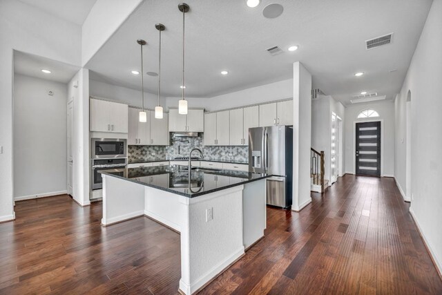 252 Sabino Dr, Buda, TX 78610 - kitchen with appliances with stainless steel finishes, dark countertops, tasteful backsplash, an island with sink, and recessed lighting