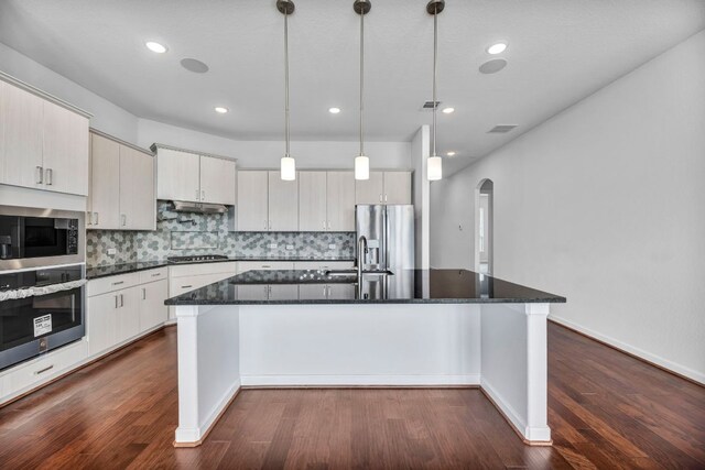 252 Sabino Dr, Buda, TX 78610 - kitchen with appliances with stainless steel finishes, arched walkways, a sink, under cabinet range hood, and a kitchen island with sink