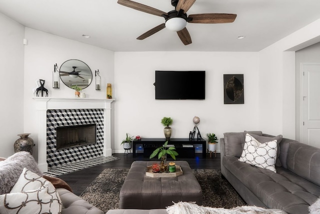 living area featuring a tile fireplace, a ceiling fan, and wood finished floors