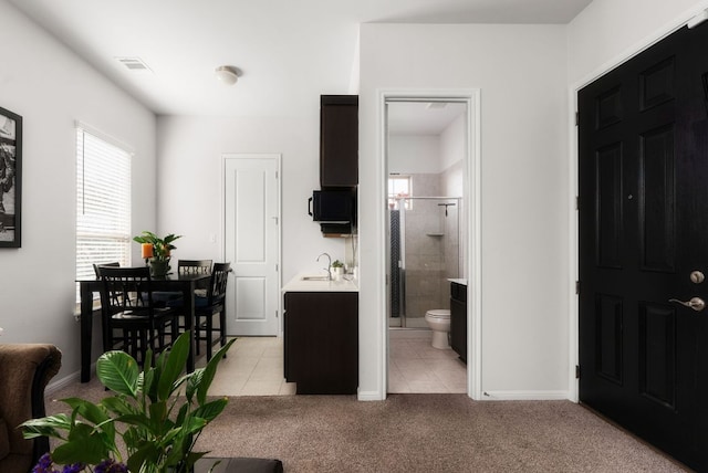 interior space featuring visible vents, baseboards, light colored carpet, and light tile patterned flooring