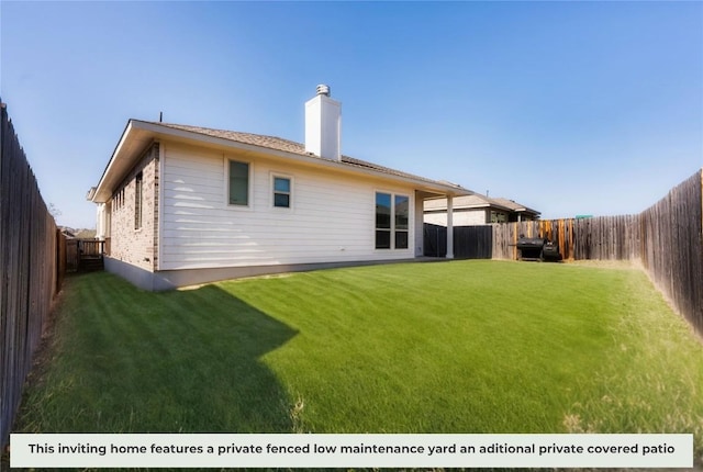 back of house with a fenced backyard, a chimney, and a yard