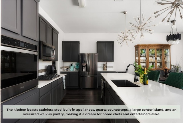 kitchen featuring a sink, light countertops, appliances with stainless steel finishes, a notable chandelier, and backsplash