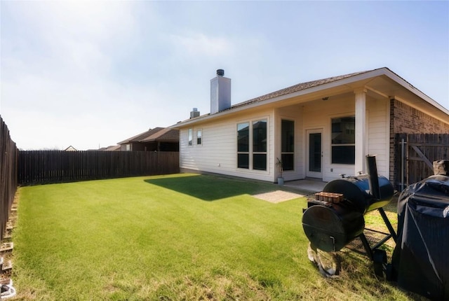 back of property featuring a fenced backyard, a lawn, and a chimney