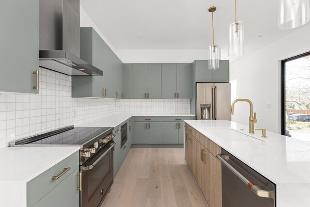 802 Philco Dr Unit 1, Austin, TX 78745 - kitchen featuring wall chimney range hood, appliances with stainless steel finishes, light wood-style floors, decorative backsplash, and decorative light fixtures