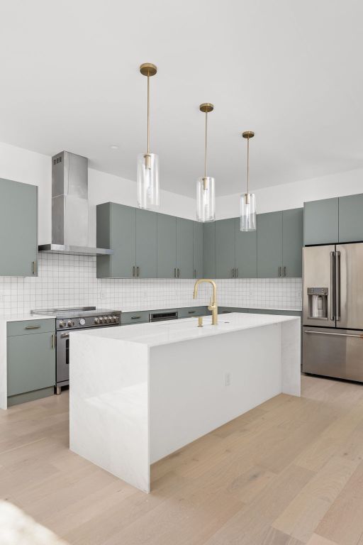 802 Philco Dr Unit 1, Austin, TX 78745 - kitchen featuring stainless steel appliances, wall chimney exhaust hood, decorative backsplash, and light countertops