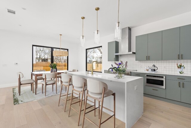 802 Philco Dr Unit 1, Austin, TX 78745 - kitchen with wall chimney exhaust hood, oven, light wood finished floors, backsplash, and light countertops