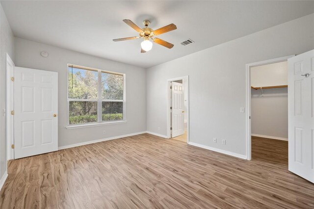 5709 Hudson Bend Rd, Austin, TX 78734 - unfurnished bedroom featuring wood finished floors, a spacious closet, a closet, a ceiling fan, and ensuite bathroom