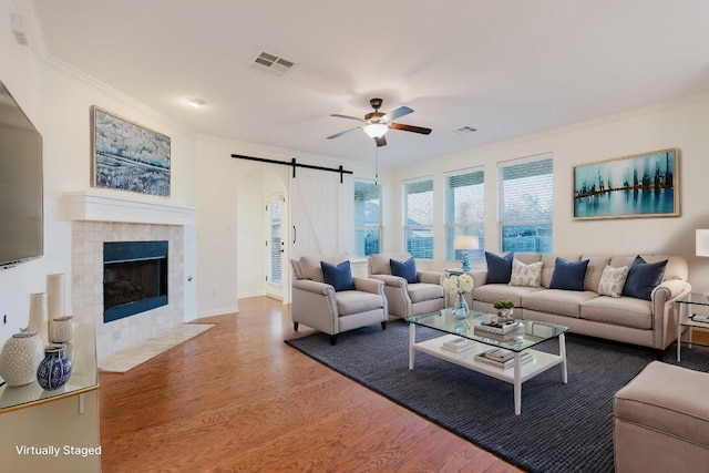 422 Village Commons Blvd, Georgetown, TX 78633 - living area featuring a barn door, a ceiling fan, crown molding, wood finished floors, and a fireplace