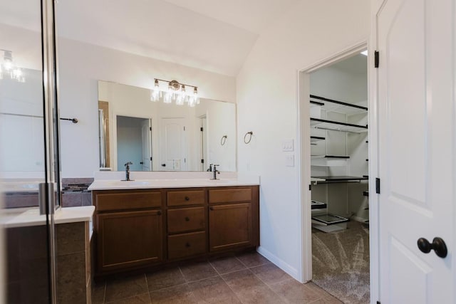 422 Village Commons Blvd, Georgetown, TX 78633 - bathroom with double vanity, a walk in closet, lofted ceiling, tile patterned floors, and baseboards