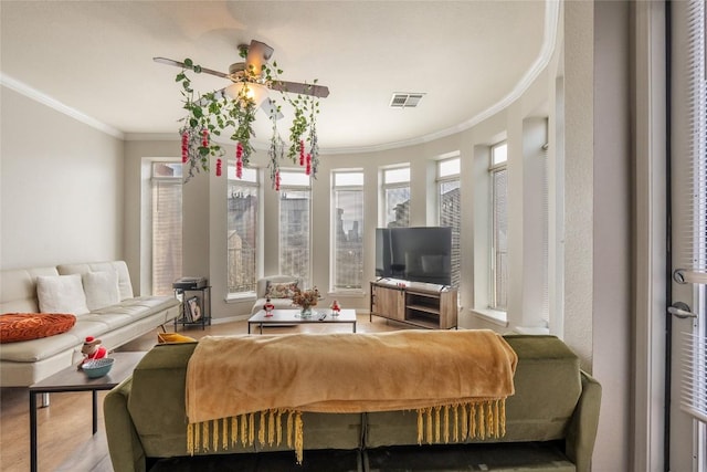 living area with visible vents, ornamental molding, and ceiling fan