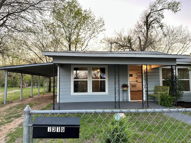 view of front of property with a porch, an attached carport, and fence