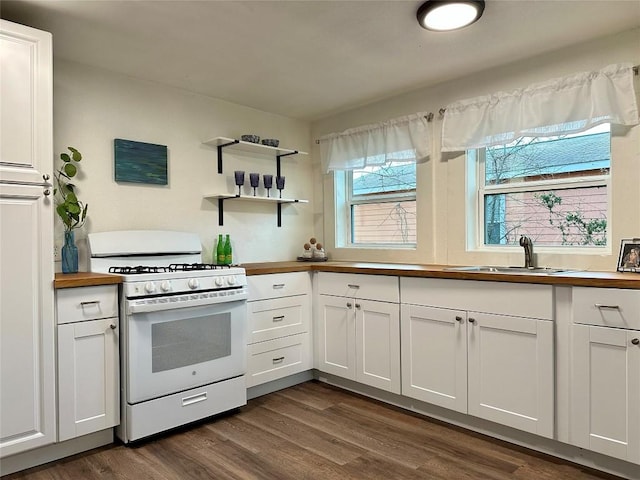 kitchen with white gas range oven, butcher block countertops, white cabinetry, and a sink