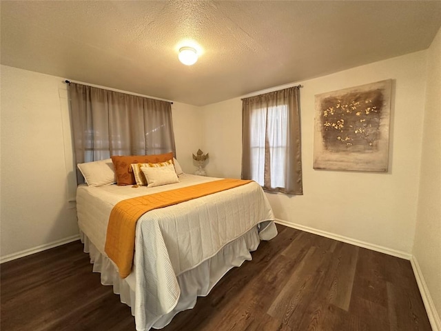 bedroom featuring a textured ceiling, wood finished floors, and baseboards