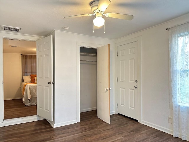 unfurnished bedroom featuring dark wood-style floors, visible vents, a closet, and baseboards