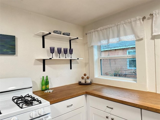 kitchen with gas range gas stove, open shelves, white cabinetry, and butcher block counters