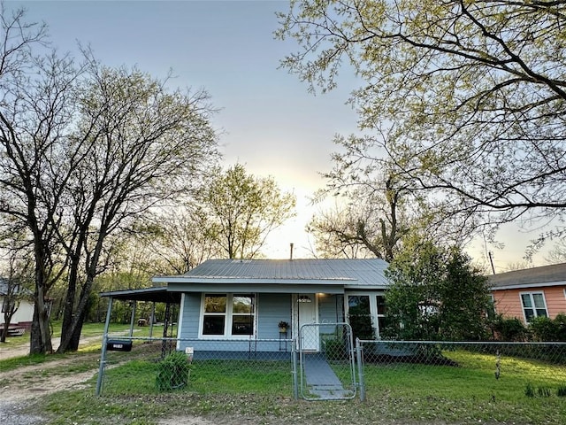 bungalow-style house featuring a carport, metal roof, a gate, and a fenced front yard