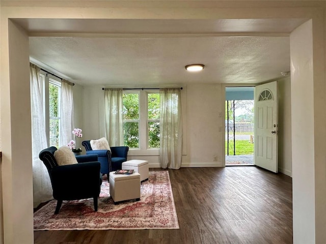 living room with dark wood-type flooring, plenty of natural light, a textured ceiling, and baseboards