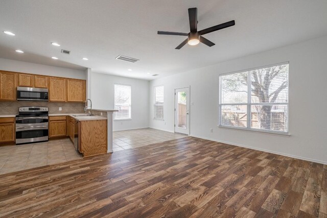 101 Verde Ranch Loop, Leander, TX 78641 - kitchen featuring stainless steel appliances, a sink, wood finished floors, a peninsula, and ceiling fan