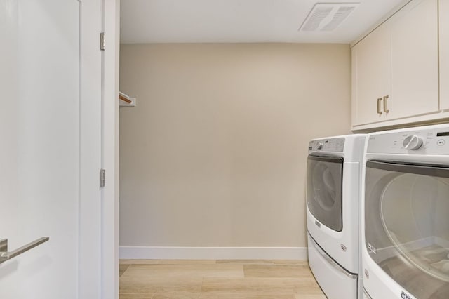 8702 Silverhill Ln, Austin, TX 78759 - laundry area featuring washer and dryer, cabinet space, light wood-type flooring, and baseboards