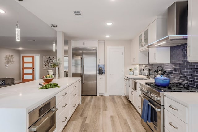 8702 Silverhill Ln, Austin, TX 78759 - kitchen with high end appliances, wall chimney range hood, light wood finished floors, light countertops, and backsplash