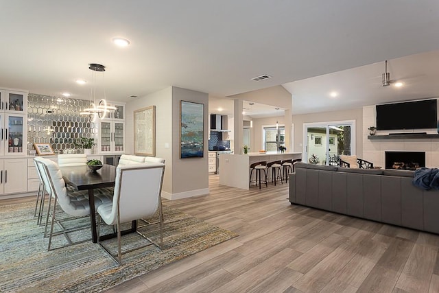 8702 Silverhill Ln, Austin, TX 78759 - dining area featuring light wood-style floors, a fireplace, a chandelier, baseboards, and recessed lighting