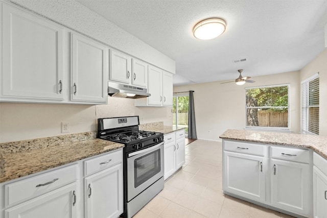11921 Tanglebriar Trl, Austin, TX 78750 - kitchen with stainless steel gas range, under cabinet range hood, ceiling fan, white cabinets, and light stone counters