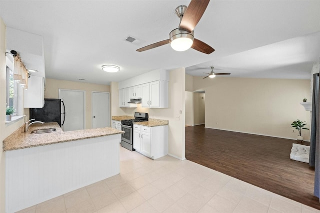 11921 Tanglebriar Trl, Austin, TX 78750 - kitchen featuring stainless steel gas stove, freestanding refrigerator, a sink, a ceiling fan, and white cabinetry