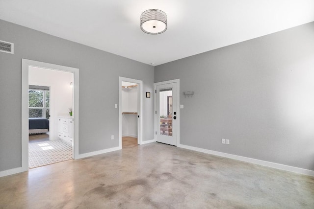 631 Lakeside Dr, Wimberley, TX 78676 - unfurnished bedroom featuring a closet, connected bathroom, baseboards, concrete flooring, and a spacious closet