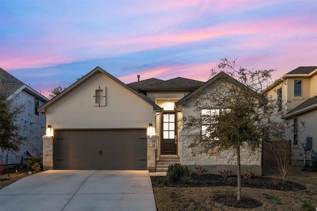 view of front of home with stone siding, driveway, and stucco siding
