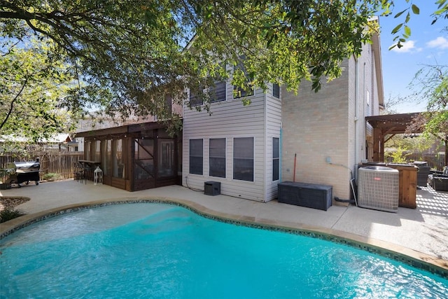 view of pool with a sunroom, a patio area, fence, and central air condition unit