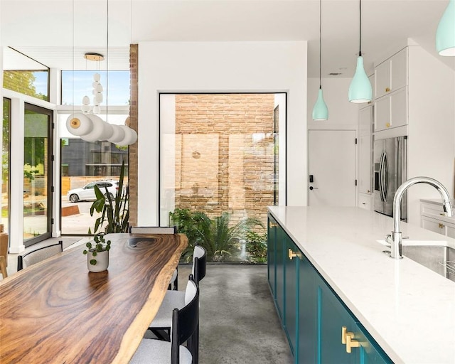 2012 Arpdale St, Austin, TX 78704 - kitchen featuring stainless steel fridge, plenty of natural light, concrete flooring, and hanging light fixtures