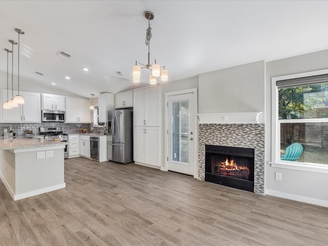 10310 Bilbrook Pl, Austin, TX 78748 - kitchen with stainless steel appliances, white cabinetry, vaulted ceiling, decorative backsplash, and light wood-type flooring