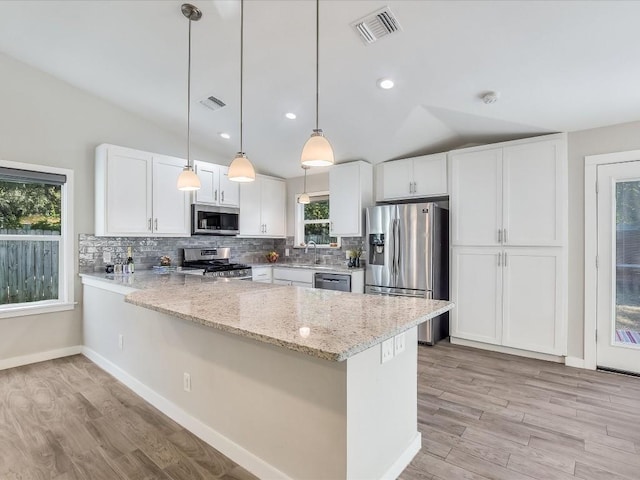 10310 Bilbrook Pl, Austin, TX 78748 - kitchen featuring stainless steel appliances, vaulted ceiling, a peninsula, light wood-style flooring, and tasteful backsplash