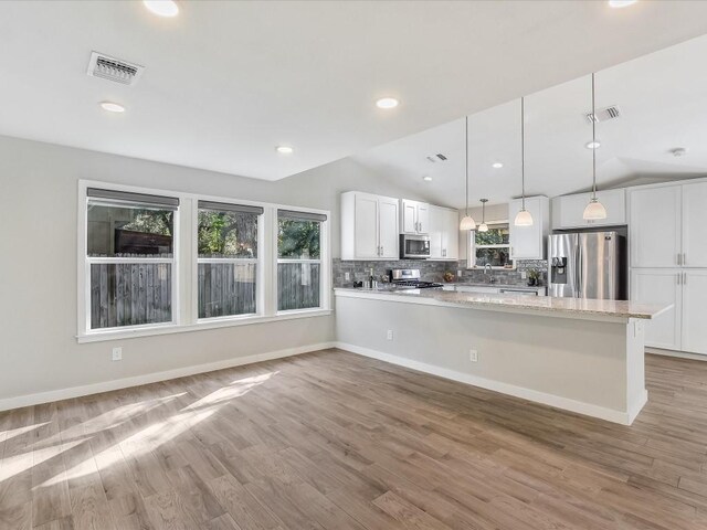 10310 Bilbrook Pl, Austin, TX 78748 - kitchen featuring stainless steel appliances, lofted ceiling, white cabinetry, tasteful backsplash, and a peninsula