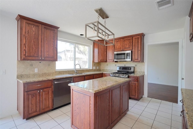 8521 Racine Trl, Austin, TX 78717 - kitchen featuring appliances with stainless steel finishes, a sink, backsplash, light tile patterned flooring, and a center island