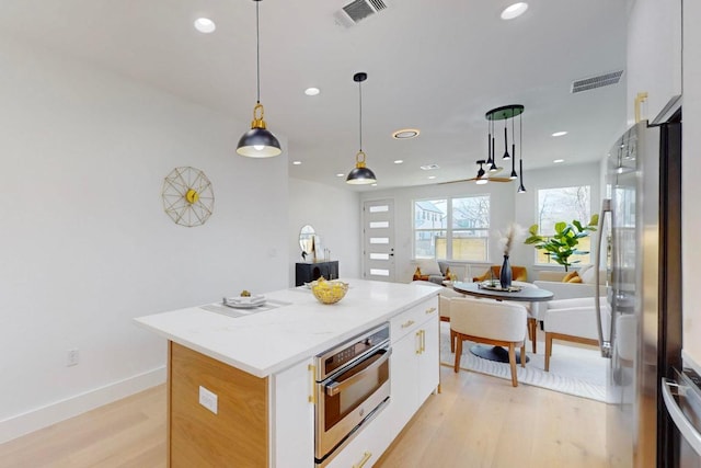 4800 Prock Ln Unit A, Austin, TX 78721 - kitchen with appliances with stainless steel finishes, a kitchen island, white cabinetry, light wood-type flooring, and hanging light fixtures