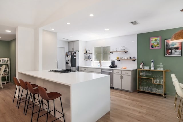 2205 Trede Dr, Austin, TX 78745 - kitchen featuring stainless steel appliances, light wood finished floors, a breakfast bar area, a sink, and light countertops