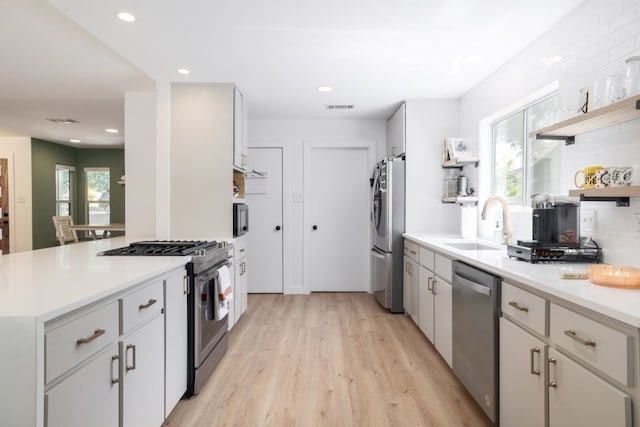 2205 Trede Dr, Austin, TX 78745 - kitchen with appliances with stainless steel finishes, a sink, light wood-style floors, tasteful backsplash, and open shelves