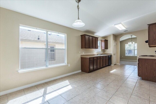 12900 Noche Clara Dr, Del Valle, TX 78617 - kitchen featuring dark brown cabinets, a sink, hanging light fixtures, light countertops, and arched walkways
