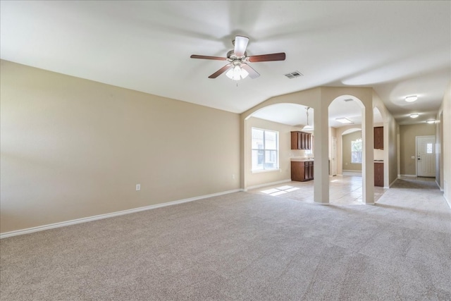 12900 Noche Clara Dr, Del Valle, TX 78617 - unfurnished living room featuring light colored carpet, ceiling fan, vaulted ceiling, arched walkways, and baseboards