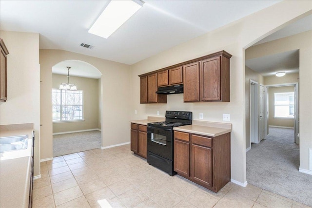 12900 Noche Clara Dr, Del Valle, TX 78617 - kitchen with black range, under cabinet range hood, light colored carpet, arched walkways, and a chandelier